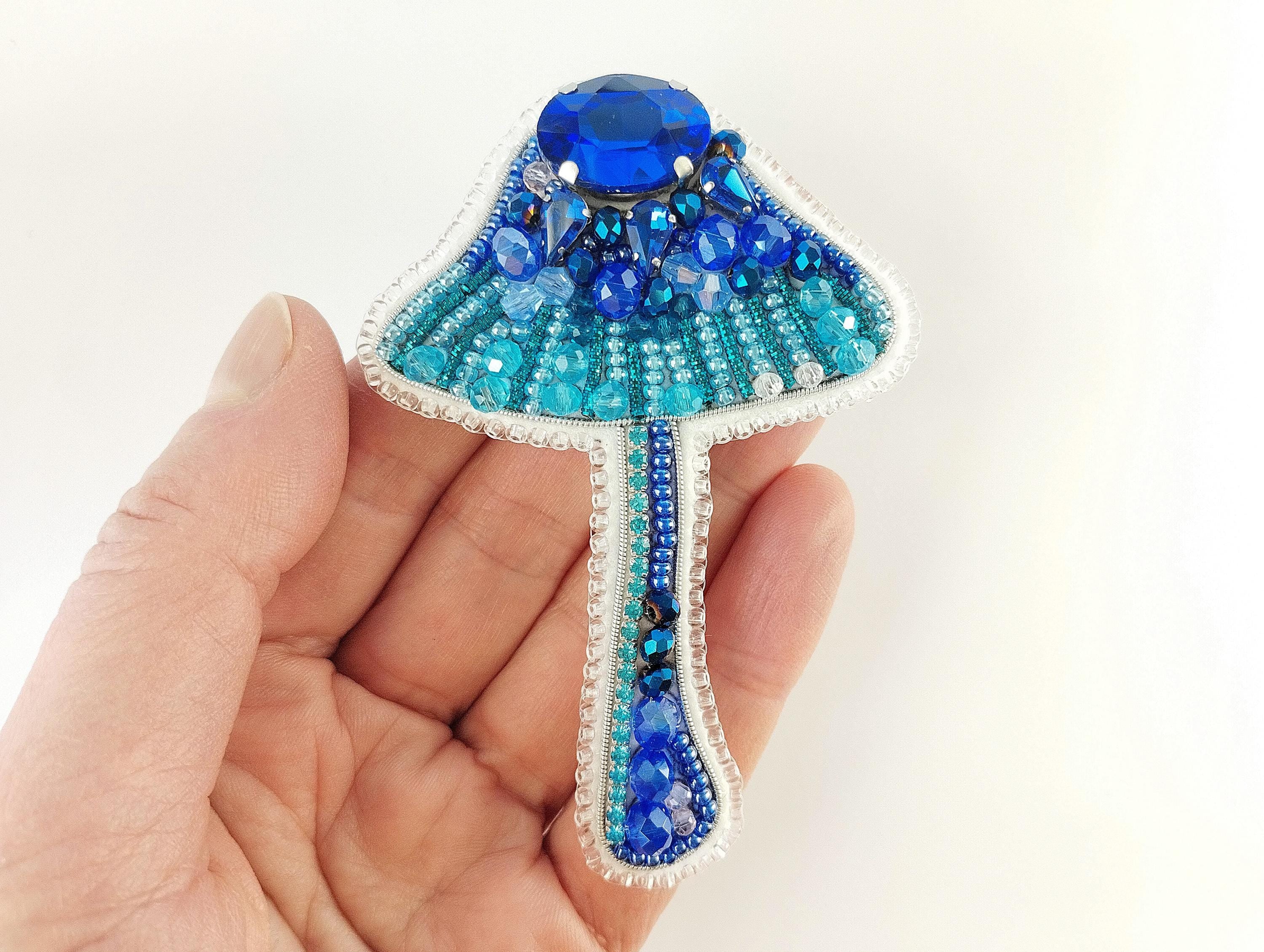 a hand holding a blue and white brooch